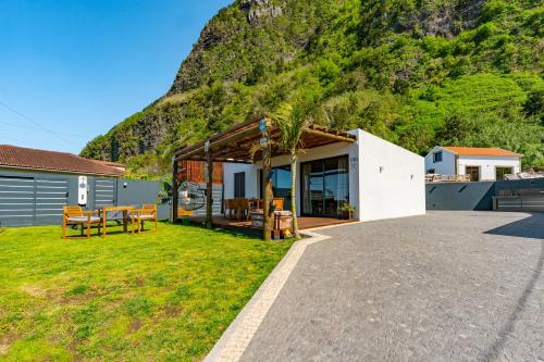 a house with a mountain in the background at Fajã Lodges - House Ash in São Vicente