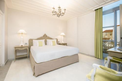 a white bedroom with a bed and a window at Micra Anglia Boutique Hotel & Spa in Andros