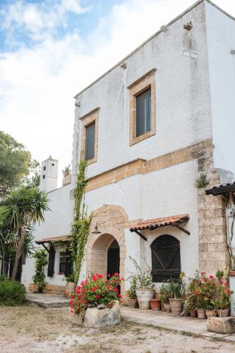 TorchiaroloにあるMasseria Piutriの前に鉢植えが置かれた白い建物