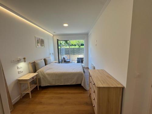 a bedroom with a bed and a table and a window at Piso de lujo con gran terraza in Sanxenxo