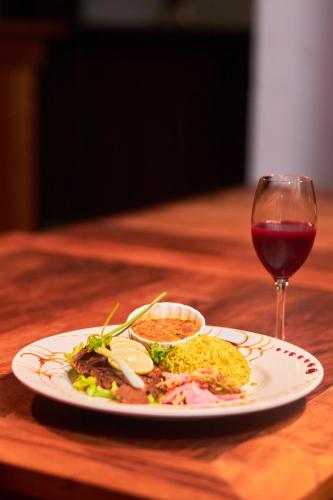 a plate of food and a glass of red wine at Andasibe Sifaka Lodge in Andasibe