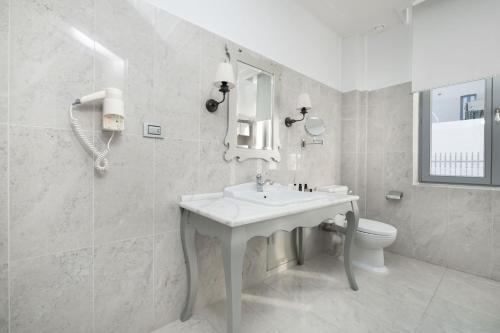 a white bathroom with a sink and a toilet at Micra Anglia Boutique Hotel & Spa in Andros