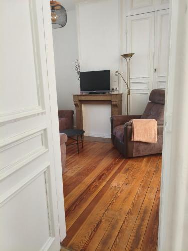 a living room with a couch and a television at AGV Gîte in Audruicq
