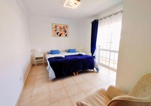 a bedroom with a bed with blue sheets and a window at Villa Serena in Olhão