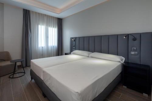 a bedroom with a large white bed and a chair at Leflet Sanlucar in Sanlúcar la Mayor