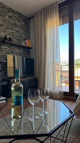 a bottle of wine and two wine glasses on a glass table at Balcón del Júcar delux in Tragacete