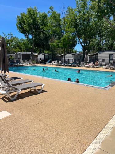une piscine avec des chaises et des gens dans l'eau dans l'établissement Mobil-home Camping -La Marine - 4 Étoiles - Grau du Roi - B038, au Grau-du-Roi