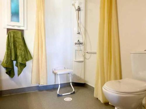 La salle de bains est pourvue de toilettes et d'un rideau de douche jaune. dans l'établissement Camping 5 étoiles - Piscine - eeaibb, à Saint-Georges-dʼOléron