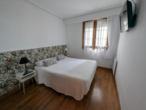 a white bedroom with a bed and a window at Apartamento con Encanto y Vistas al Mar en Getaria in Getaria