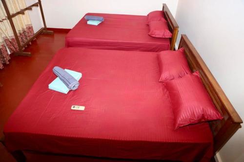 two beds with red sheets and red pillows at Baski Guest House in Jaffna