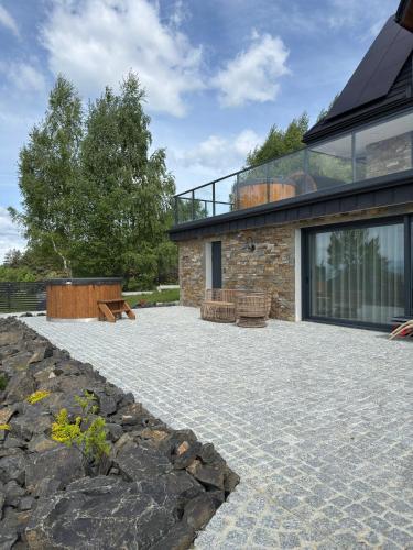 a stone patio with benches in front of a house at Gorczański Lux Chalet in Szlembark