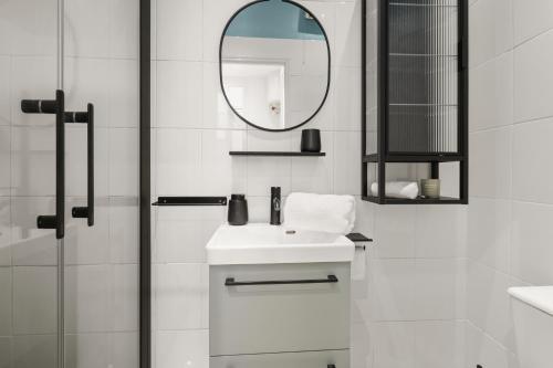 une salle de bain blanche avec un lavabo et un miroir dans l'établissement Le Nid Azur à 200 Mètres de la Plage, à Vallauris