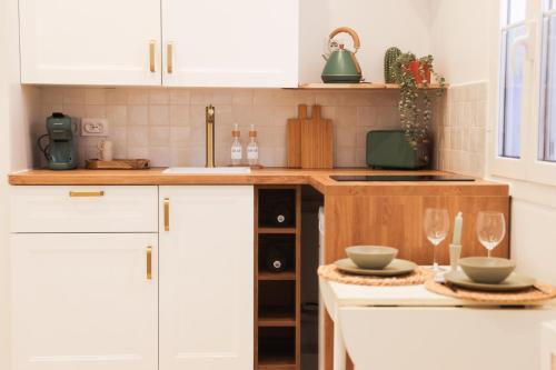 une cuisine avec des armoires blanches et deux assiettes et verres à vin dans l'établissement Le Nid Azur à 200 Mètres de la Plage, à Vallauris