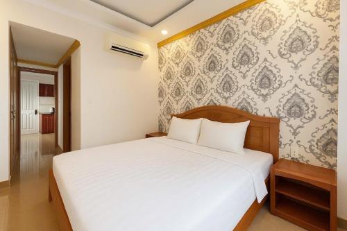 1 dormitorio con cama blanca y pared en K&T Hotel- Aparment SaiGon Center, en Ho Chi Minh