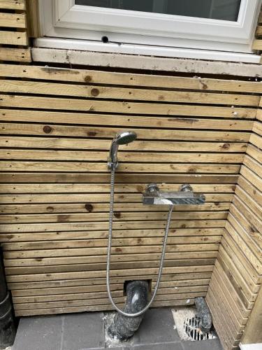 a shower with a hose attached to a wooden wall at Sunbeam House 1 Morecambe Pet Friendly in Morecambe