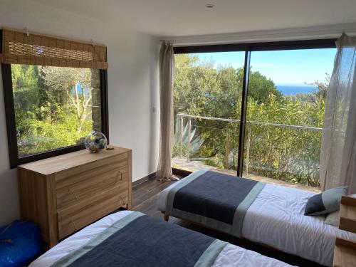 une chambre avec deux lits et une grande fenêtre dans l'établissement Villa Mariposa Gaou Bénat, à Bormes-les-Mimosas