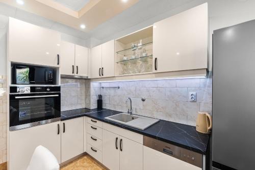 a kitchen with white cabinets and a sink at APP Sandro with Common Pool in Poreč