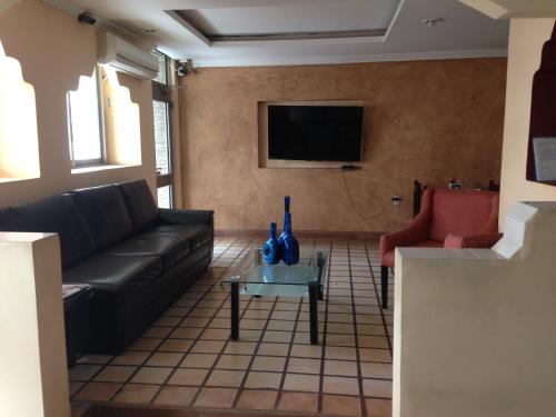 sala de estar con sofá negro y TV en Hotel Moreno, en Coatzacoalcos