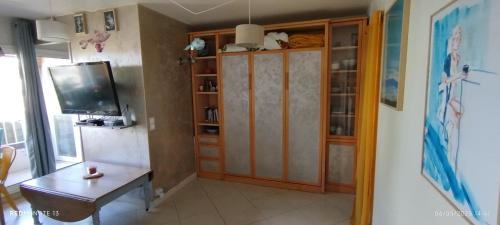 - un salon avec une télévision et une armoire en bois dans l'établissement Studio with balcony near city center, à Courseulles-sur-Mer