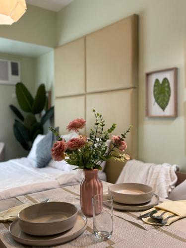 a table with two plates and a vase with flowers at Avida Towers Riala T2, L&D Stays, Coffee Machine in Cebu City
