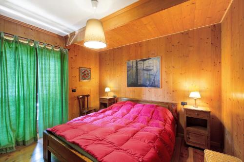 een groot rood bed in een kamer met houten wanden bij Appartamento Serdes Big C2 in San Vito di Cadore