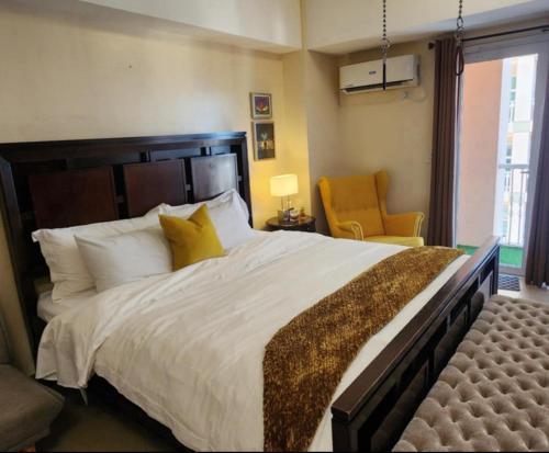 a bedroom with a large bed and a chair at The Venice Luxury Residences Condominium 28B Bellini, McKinley Hill, Taguig City, Philippines in Manila