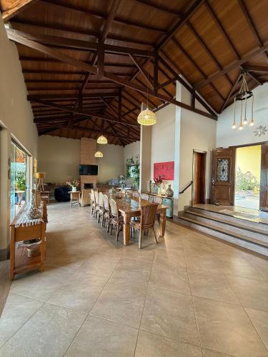 a large dining room with a table and chairs at 7 QUARTOS, sendo 6 SUÍTES, PISCINA AQUECIDA borda infinita na REPRESA de DELFINÓPOLIS in Ibiraci