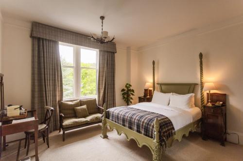 a bedroom with a bed and a chair and a window at Craigellachie Hotel of Speyside in Craigellachie
