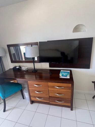 a desk with a large tv and a blue chair at Hôtel Le Roy in Christ Church
