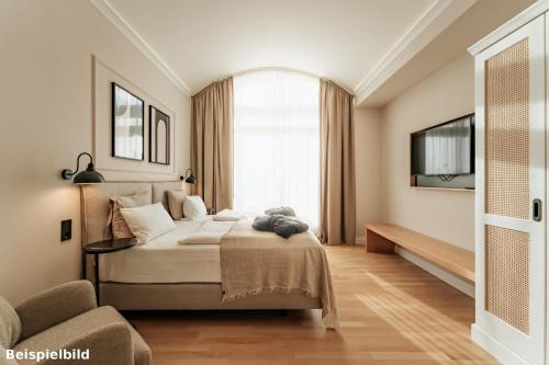 a bedroom with a large bed and a window at Strandhotel Kurhaus Juist in Juist