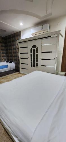a bedroom with a white bed and a chest of drawers at مؤسسة مقهي حلا ثلاثه لتقديم المشروبات in Al Qurayyat
