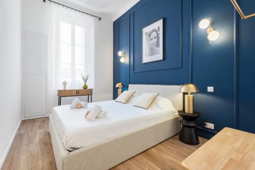 une chambre avec un grand lit aux murs bleus dans l'établissement Appartement Prado - Welkeys, à Cannes