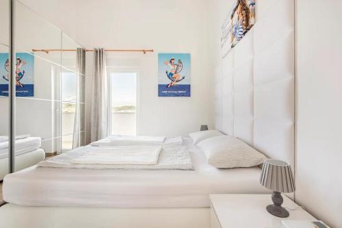 a white bedroom with two beds and a window at Villa Maritime - Exklusive Strandvilla mit beheiztem Pool, Grillhütte & Meerblick bei Zadar in Ljubač