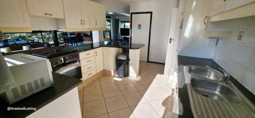 a kitchen with a sink and a stove at Beachwood Cottage in Margate