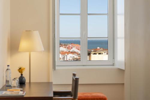 an office with a desk and a window with a view of the ocean at Memmo Alfama - Design Hotels in Lisbon