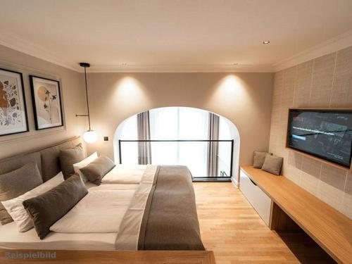 a bedroom with a large bed and a flat screen tv at Strandhotel Kurhaus Juist in Juist