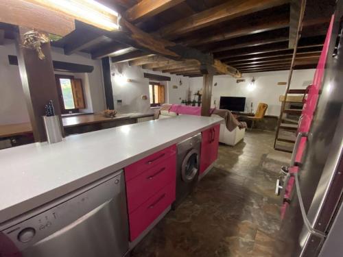 a kitchen with pink cabinets and a living room at Cabaña Pasiega Lucas in Bustantegua