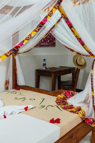 a bed with a canopy in a room with a table at Shoki Shoki Guest House in Zanzibar City