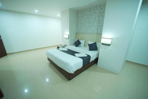 a bedroom with a white bed with blue pillows at Hotel Occassia Bliss Miyapur in Lingampalli