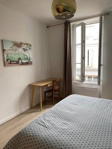 a bedroom with a bed and a table and a window at Maison Frères Prêcheurs in La Rochelle