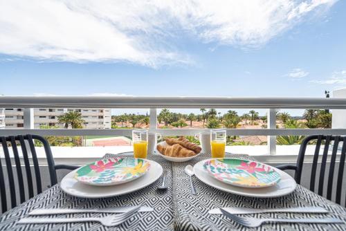 a table with two plates of food and two glasses of orange juice at Holiday Dream Maspalomas in Maspalomas
