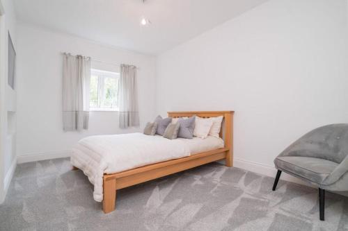 a white bedroom with a bed and a chair at The Luxury Country Home in Aughton