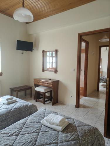 a bedroom with two beds and a desk at Filoxenia in Tsagarada
