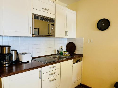 Ferienwohnung Strandlust in der Villa Seeadler Binz في بينز: مطبخ بخزائن بيضاء ومغسلة وميكروويف