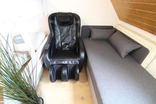 a couch in a small room with a chair at Hotel Ulm Zentrum - Komplettes Zimmer, Hochbett, Android TV & eigenem Bad - perfekt für Familien & Gruppen in Ulm