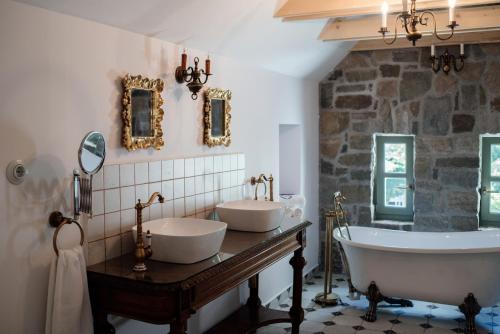a bathroom with two sinks and a stone wall at Hazai Provence in Kapolcs