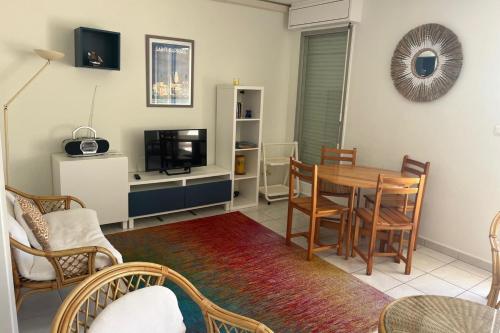 - un salon avec une table, des chaises et une télévision dans l'établissement Residence quiet and wooded near beach, à Saint-Raphaël