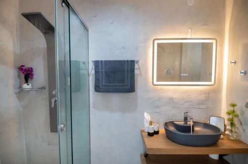 a bathroom with a sink and a glass shower at Archontiki Veranda - Design Villa in Crete with Heated Pool, Jacuzzi & Dreamy Views in Arkhondikí