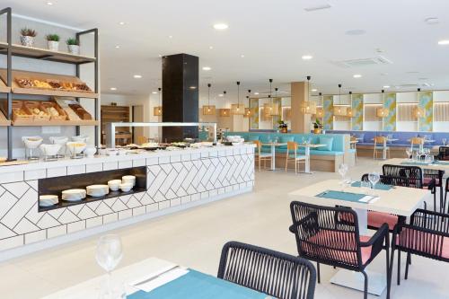 un ristorante con tavoli e sedie e una panetteria di Universal Aparthotel Elisa a Playa de Muro