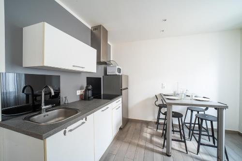 - une cuisine avec un évier et une table avec des tabourets dans l'établissement Villa Welcom 2 - 3 min à pied de la plage, à Canet